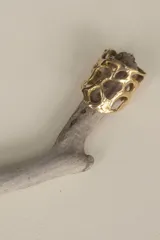 Anillo ancho de diseño orgánico y calado, con apariencia de red o magma solidificado.