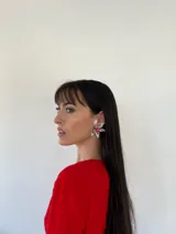 Aros con diseño de flor, compuestos por pétalos en color crema y un centro decorado con cristales en tonos rosados.