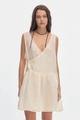 Vestido corto fluido de tacto sedoso en color marfil, con escote en V cruzado, sin mangas y falda con volados en la parte inferior.