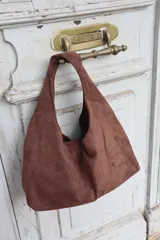 Cartera tipo hobo de gamuza negra, con diseño minimalista y asa integrada.