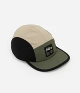 Gorra tipo 5 panel confeccionada en microfibra de poliamida, con diseño de bloques de colores en beige, negro y verde oliva. Presenta visera recta, cierre posterior ajustable y etiqueta frontal con gráfico y frase Stay Grounded.