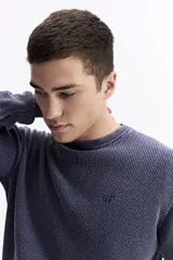 Sweater de hombre con textura waffle, color verde oliva desgastado (acid wash), cuello redondo y puños y ruedo acanalados. Presenta un pequeño logo bordado en el pecho.