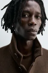 Abrigo marrón de corte recto, con cuello mao y cierre frontal abotonado. Tiene bolsillos laterales y abertura en la parte trasera. Confeccionado en tejido de lana.