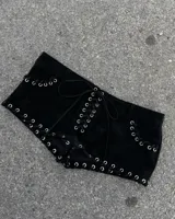 Short de gamuza negra con diseño de cordones cruzados y ojales metálicos plateados en la parte frontal y los laterales.