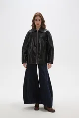 Campera de eco-cuero negro con acabado brillante, cuello camisero, cierre frontal completo y diseño de corte holgado.