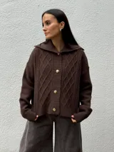 Cardigan de punto color marrón con diseño de rombos y textura, cuello amplio y cierre frontal con botones dorados.