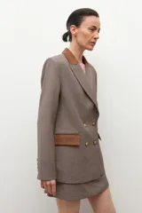 Blazer de corte sastre con estampado de cuadros pequeños en tonos tierra. Presenta solapas y detalles en los bolsillos de gamuza en color marrón, cierre frontal de doble botonadura y estructura entallada.