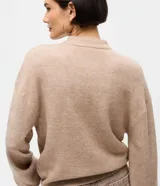 Suéter de punto color marrón chocolate, con cuello alto y mangas largas con puños ajustados. Presenta un diseño de corte corto y holgado.