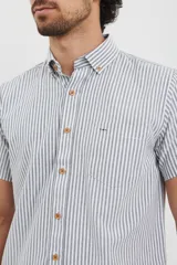 Camisa de manga corta a rayas verticales blancas y celestes, con cuello abotonado y bolsillo en el pecho.