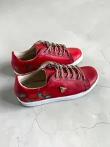 Championes de cuero rojo con detalles pintados a mano en el talón, suela blanca de goma y cordones beige.