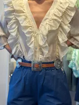 Cinturón marrón de cuero con hebilla plateada rectangular con diseño de flores y apliques metálicos circulares con diseño de flores.