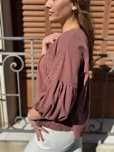 Blusa color chocolate de diseño holgado, con cuello redondo, frunce frontal y mangas abullonadas con puños ajustados.