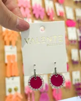 Aros colgantes con aro de acero plateado y dije circular fucsia con borde de strass plateado.