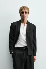 Blazer de corte cropped confeccionado en tejido con viscosa, color negro. Presenta cuello con solapas de muesca, cierre frontal de tres botones, mangas largas con puños abotonados y bolsillos de vivo en la cadera.