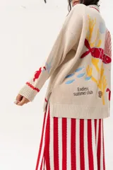 Saco oversize tejido con ilustraciones inspiradas en corales, peces, estrellas de mar y tortugas. Presenta galón picot en rojo en cartera y puños, y botones a tono.