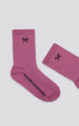 Medias 3/4 color rosa con motas blancas, confeccionadas en algodón. Presentan un logo bordado en negro con forma de tijeras en la parte superior y texto bordado en la planta del pie.