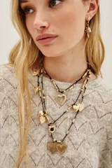 Collar de múltiples hebras negras con dijes colgantes dorados en forma de corazón de diferentes tamaños y texturas, intercalados con cuentas cilíndricas doradas.