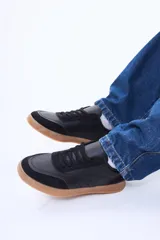 Championes urbanos de diseño versátil, confeccionados en cuero sintético (PU) color negro, con suela de goma color caramelo y detalles en gamuza sintética en la puntera.