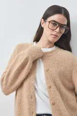 Cardigan de textura suave y efecto fluffy, color beige, con cuello redondo, cierre frontal con botones y puños acanalados.