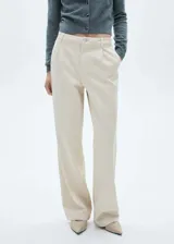 Pantalón de jean color beige, de corte recto y tiro medio. Presenta detalle de pinzas en la parte frontal, cierre de cremallera con botón y bolsillos traseros.