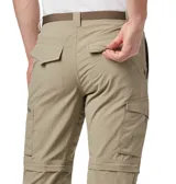 Pantalón convertible de trekking color beige, con diseño desmontable que permite transformarlo en short. Cuenta con múltiples bolsillos, incluyendo bolsillos laterales con cierre, y cintura con cinturón integrado.