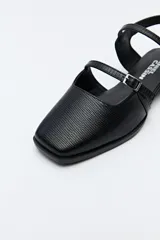 Zuecos destalonados color crema, de símil cuero, con punta cuadrada y finas tiras con hebillas ajustables. Cuentan con taco de 2,5cm de alto.