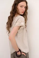 Blusa de lino color blanco con detalles de crochet en tono verde militar en los hombros, cuello redondo y manga corta.