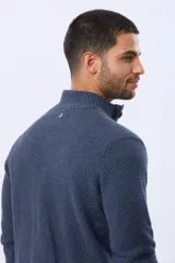 Buzo tejido texturado color verde oscuro, con cuello alto y cierre parcial de tres botones. Tiene mangas largas y un pequeño detalle de etiqueta marrón en el dobladillo inferior.