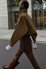 Bermuda de tiro alto color negro, con diseño de tablas frontales y detalle de eslabones metálicos dorados en la cintura. Cuenta con cierre lateral oculto.