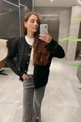 Saco tejido de lana color negro con botones marrones, de corte clásico y bolsillos frontales.