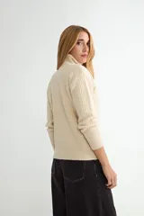 Polera de tejido de punto con cuello alto y textura acanalada en zigzag. Presenta mangas largas y puños ajustados, con un diseño clásico y versátil.