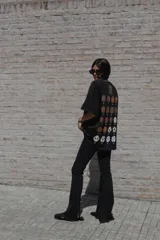 Remera oversize de algodón color negro con escote bote y costuras a la vista. Presenta una estampa en la espalda con múltiples diseños circulares que hacen referencia a balones de fútbol históricos.