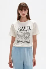 Remera de manga corta de algodón color crudo, con cuello redondo y estampa frontal de estilo astrológico con la leyenda "Travel Through The Universe".