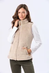 Chaleco de tejido sherpa color beige, con cuello alto y detalles en eco cuero. Diseño sin mangas que proporciona abrigo al torso manteniendo la libertad de movimiento.