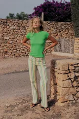 Jeans wide leg de tiro bajo con diseño de rayas verticales en tonos verde, amarillo y beige. Cuenta con cinco bolsillos, presillas para cinto y cierre frontal con cremallera y botón metálico.