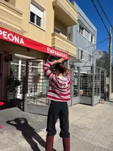 Pantalón de jean negro de tiro alto y corte recto, con detalles de roturas en las rodillas.