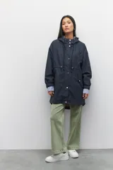 Piloto verde militar de manga larga con capucha y forro de color amarillo. Cuenta con dos bolsillos laterales con solapa, cordones ajustables, elástico en los puños, cierre y botones metálicos.