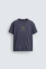 Camiseta de corte relajado con cuello redondo y manga corta. Presenta un acabado con efecto lavado que le otorga una apariencia única y desgastada. Incluye estampados a contraste en la parte frontal.