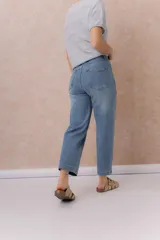 Jean de denim celeste con lavado claro, corte recto y tiro medio-alto, con diseño de cinco bolsillos y cierre frontal con botón y cremallera.