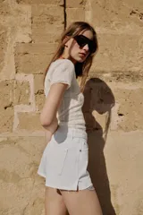 Shorts de jean tiro medio, corte mom fit, con bajo deshilachado y forro de bolsillos delanteros estampado a cuadros que asoma por debajo.