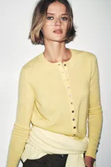 Cardigan de punto en tejido 100% cashmere, color verde oliva, con cuello redondo, manga larga y cierre frontal con botones. Presenta terminaciones en rib en puños y ruedo.