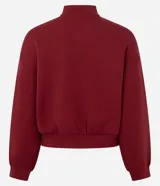 Campera deportiva tipo bomber de color bordó, con cierre frontal por cremallera, cuello redondo, mangas largas con puños elásticos y bolsillos laterales. Presenta un detalle de lettering bordado en el pecho.