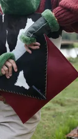 Sobre de cuero color rojo y negro con diseño de vaca y cierre con botón de guampa.