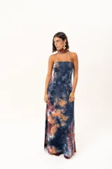 Vestido largo de corte recto y escote strapless, con estampado estilo batik en tonos azul, naranja y bordó. Incluye una bufanda larga integrada al diseño que cae desde el cuello.