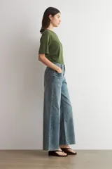 Pantalón de jean estilo wide leg con tiro medio, corte holgado y ruedo deshilachado.