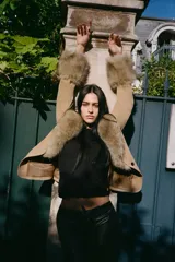 Pantalón de tiro bajo confeccionado en efecto piel, con diseño flare y detalle de lazada frontal. Presenta costuras horizontales marcadas y cierre lateral con cremallera.