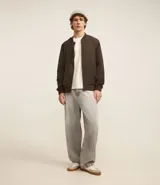 Campera bomber color beige, con cuello alto, cierre frontal con cremallera, bolsillos laterales y puños y cintura elastizados.