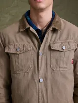 Campera de gabardina color azul marino, con cuello camisero, cierre frontal con botones metálicos y bolsillos frontales con solapa.
