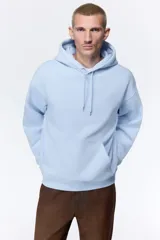 Canguro con capucha de H&M, color celeste, confeccionado en mezcla de algodón con interior cepillado. Presenta hombros caídos, cordón de ajuste en la capucha, bolsillo frontal tipo canguro y puños y bajo acanalados.