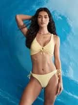 Top de bikini halter color amarillo pálido con escote en V y detalle de frunce central con cordones terminados en borlas.